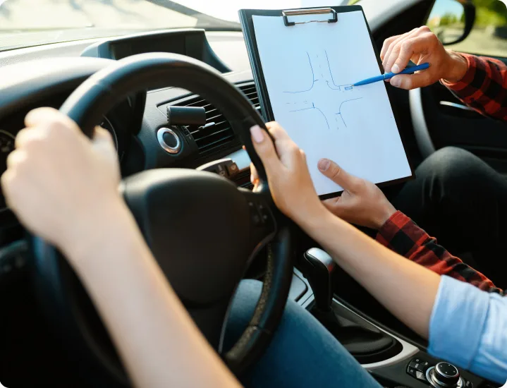 Instructor explaining an intersection on a clipboard inside the car